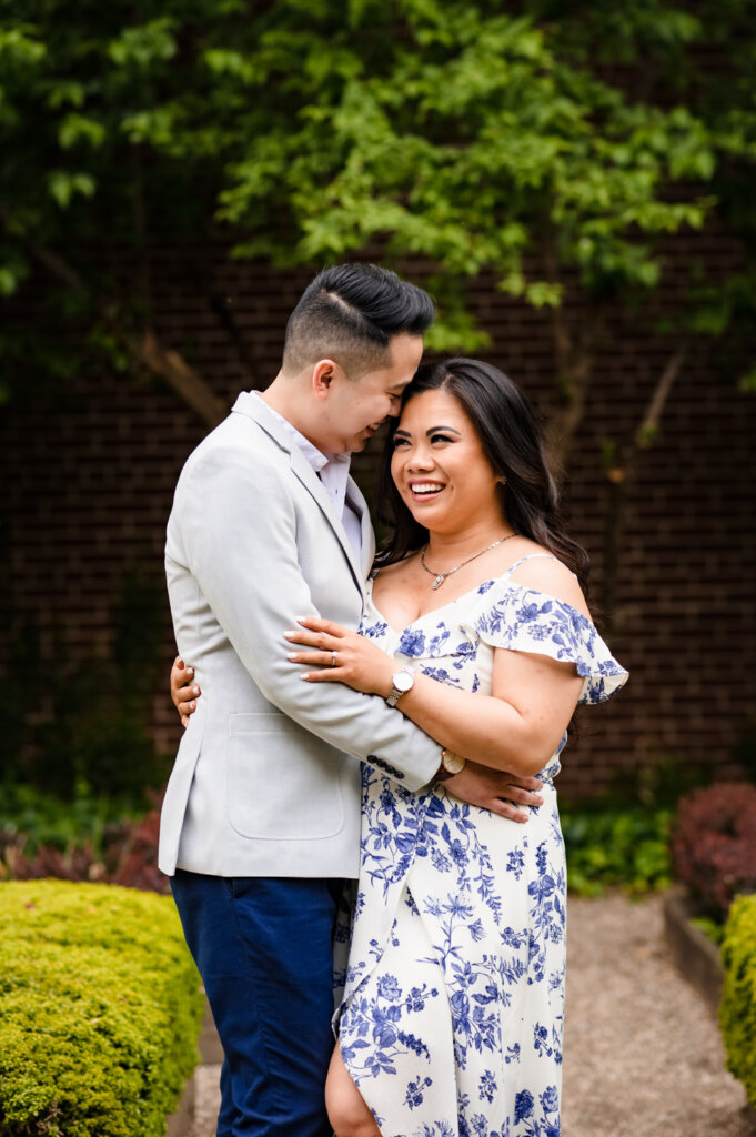 A couple is facing each other, and theman is kissing her on the forehead for their engagement photos.