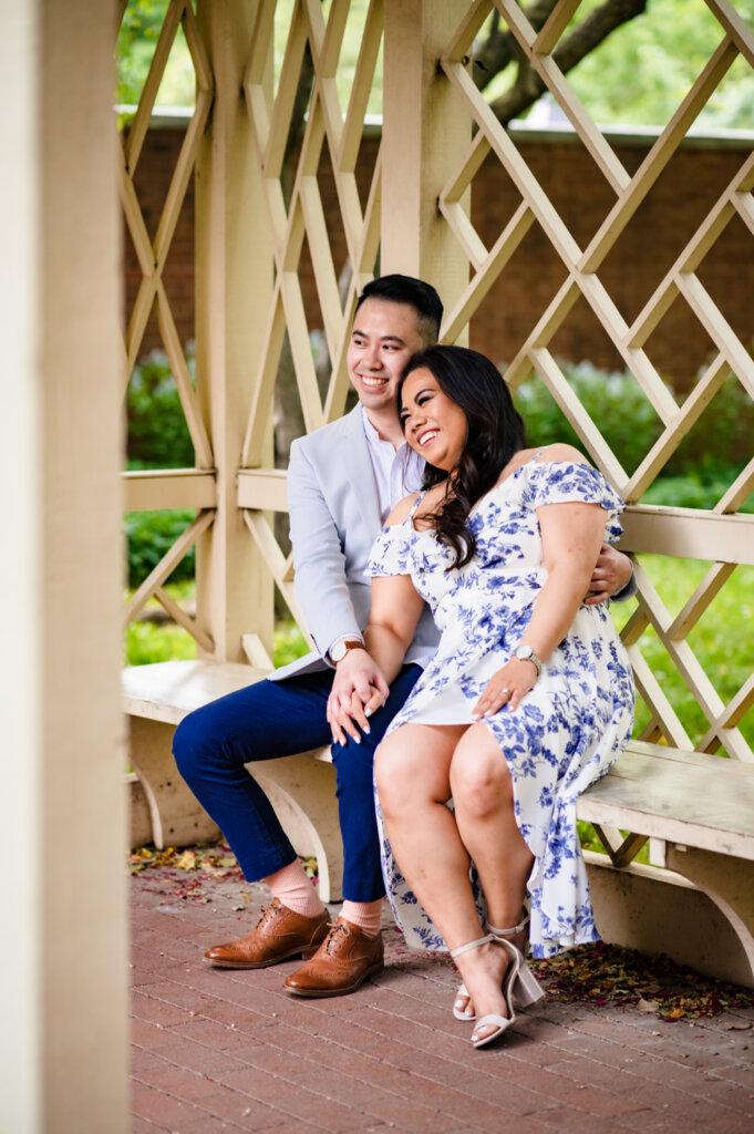 A couple is sitting side by side taking engagement photos at the 18th Century Garden gazebo in Philadelphia.