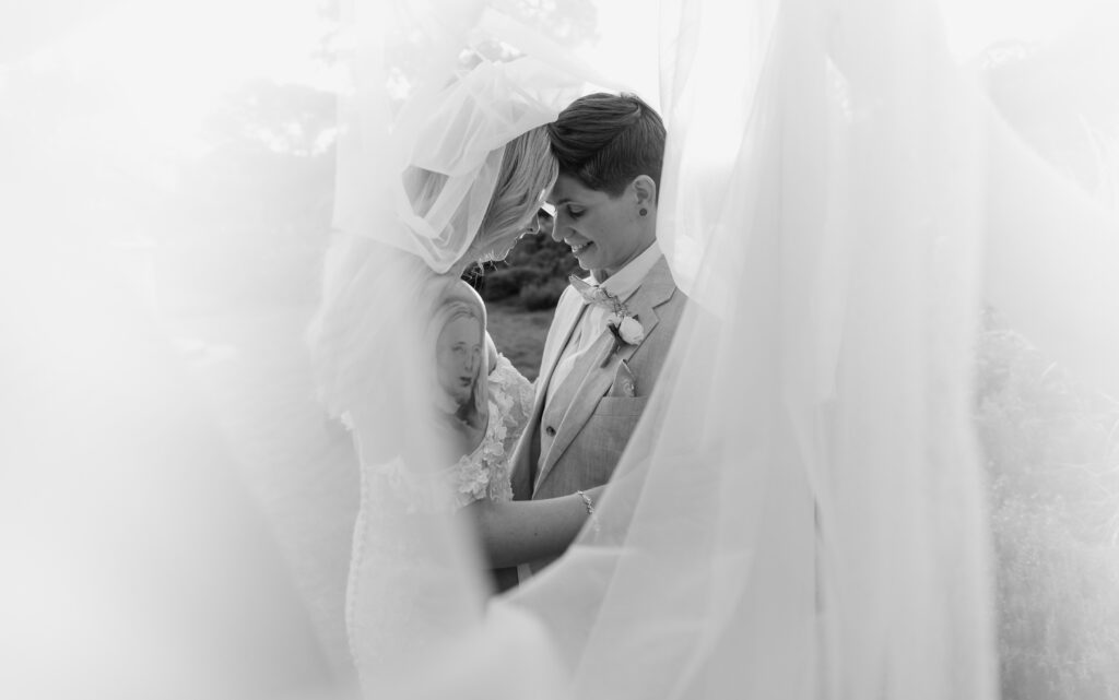 romantic editorial portrait of LGBTQ+ couple at under veil at Morris Arboretum