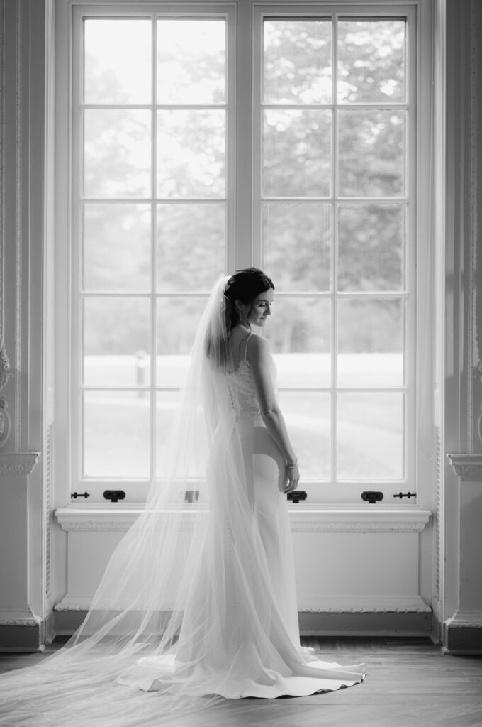 editorial film portrait of a bride by a window at Curtis Arboretum