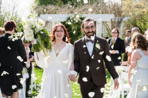 Wedding couple walking through flower petals.